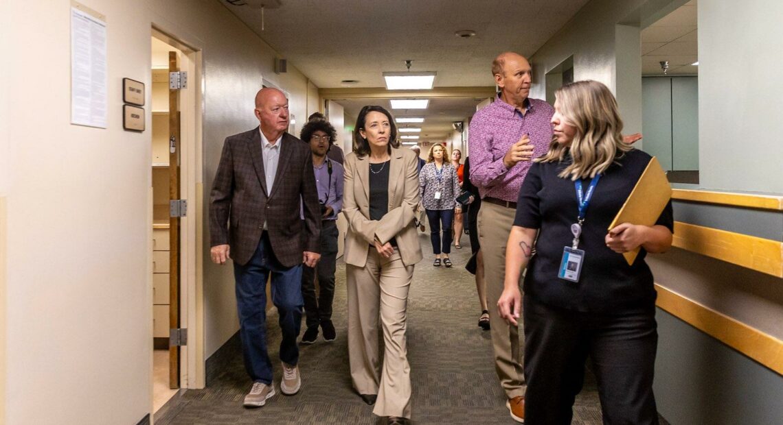 A group of four people walks down a hallway. Sen. Maria Cantwell, of Washington, is walking in the middle of the group.