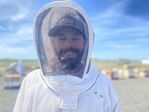 Brandon Hopkins, a bee researcher with Washington State University, smiles May 15 from inside his bee suit’s protection at the university’s honey bee research facility near Othello, Washington.