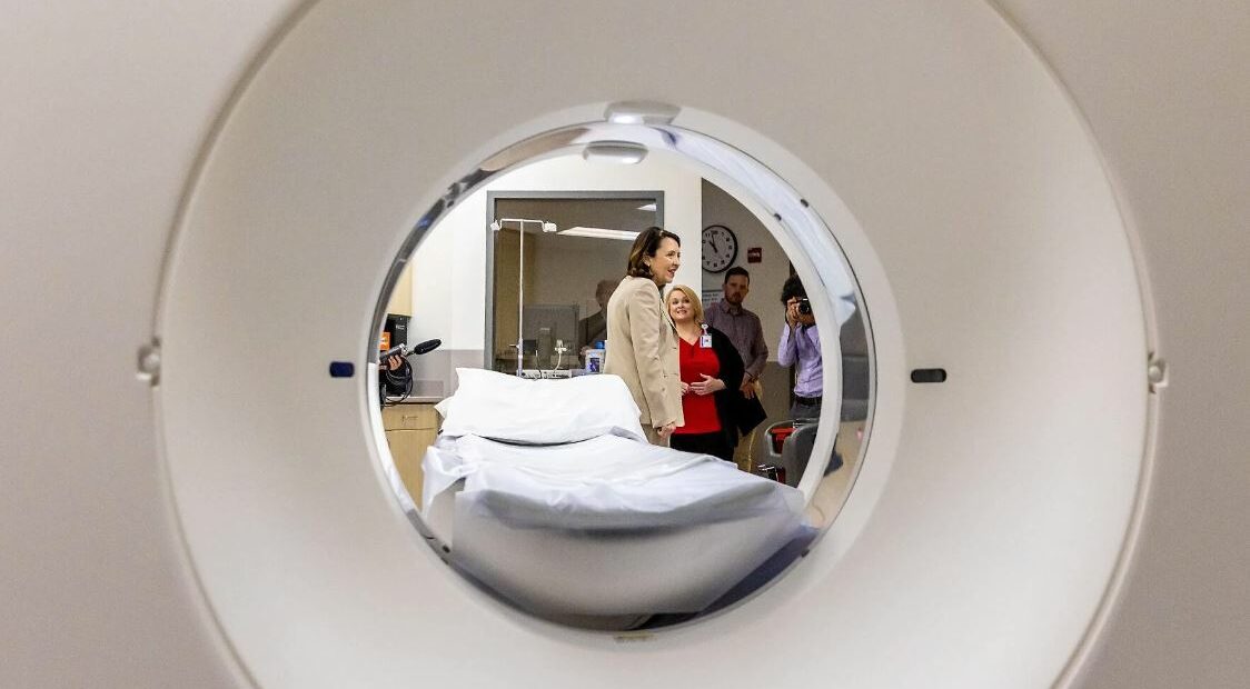 This photo is taken down the center of a CT scanner. In the opening of the scanner, Sen. Maria Cantwell is pictured to the right.