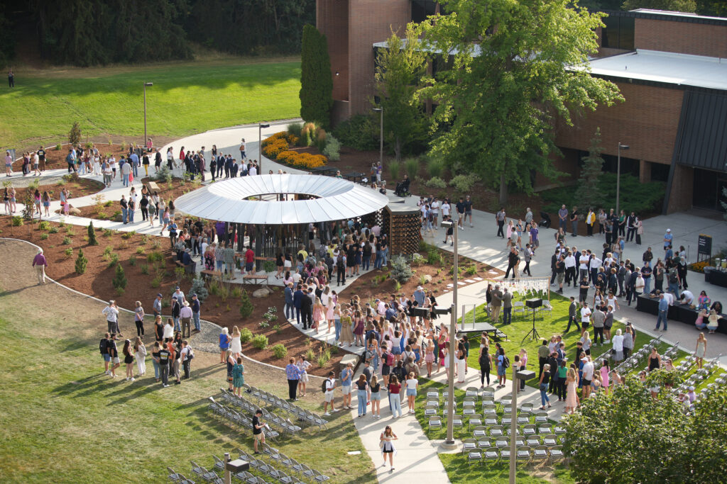 A bird's eye view shows multiple people walking through the green lawn and structure of the new Vandal Healing Garden and Memorial. 