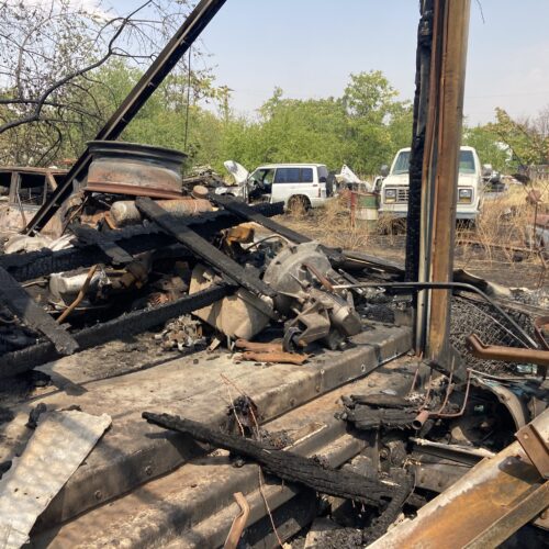 An industrial lot in Walla Walla with burned wood and vehicles.