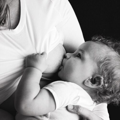 A black-and-white image of an infant being breastfed.