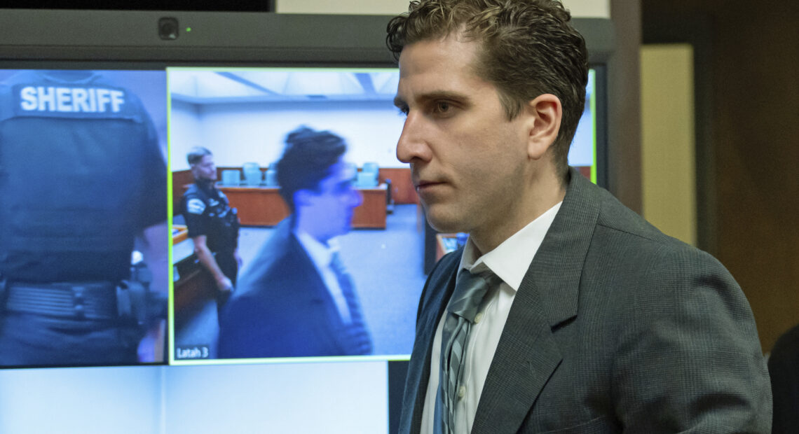 Man in suit in front of a TV screen.