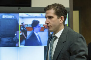 Man in suit in front of a TV screen.