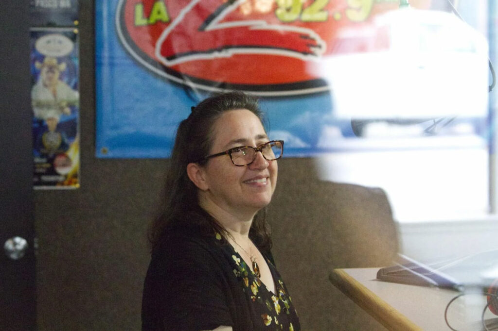 A woman sits inside a radio station while being interviewed.