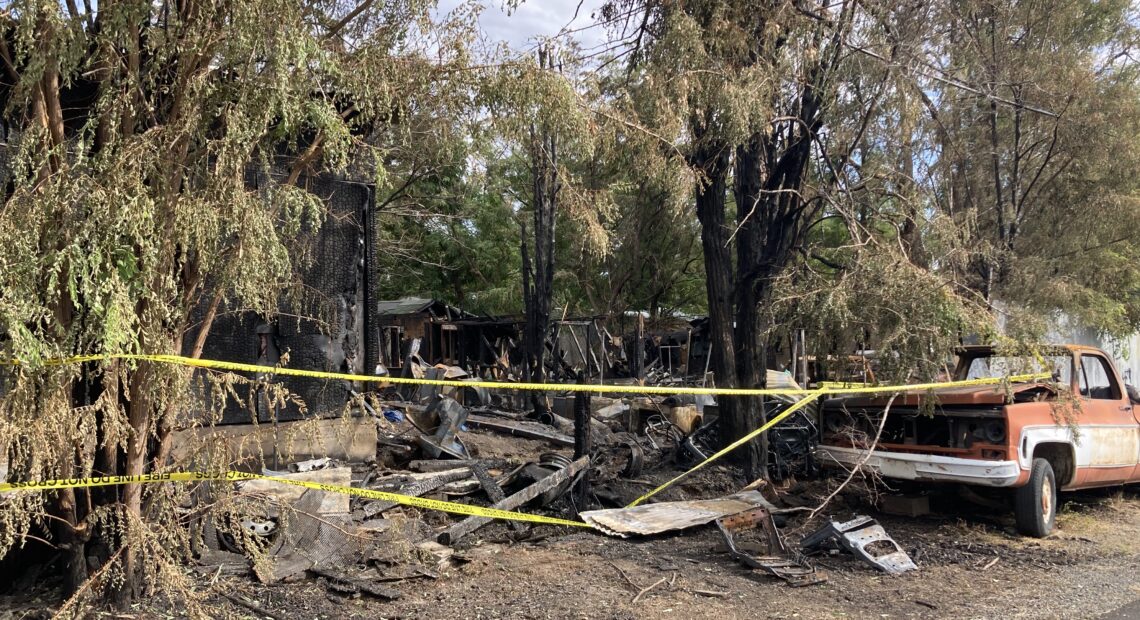 A burnt junkyard with a truck and fire tape