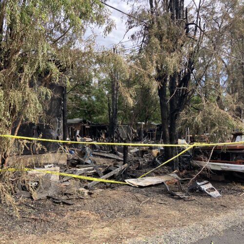 A burnt junkyard with a truck and fire tape