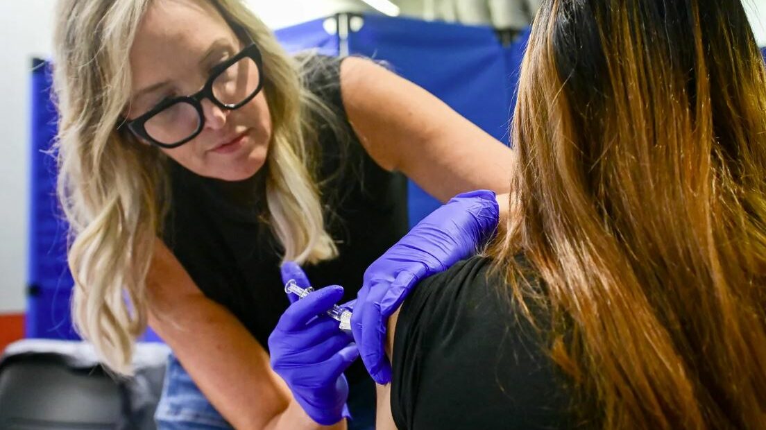 A woman administers a vaccine to another person.