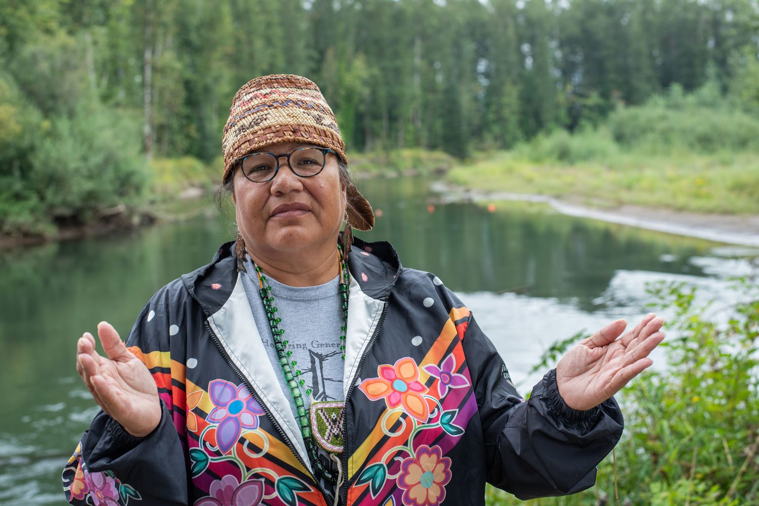 a women holds out her hands standing in front of a river