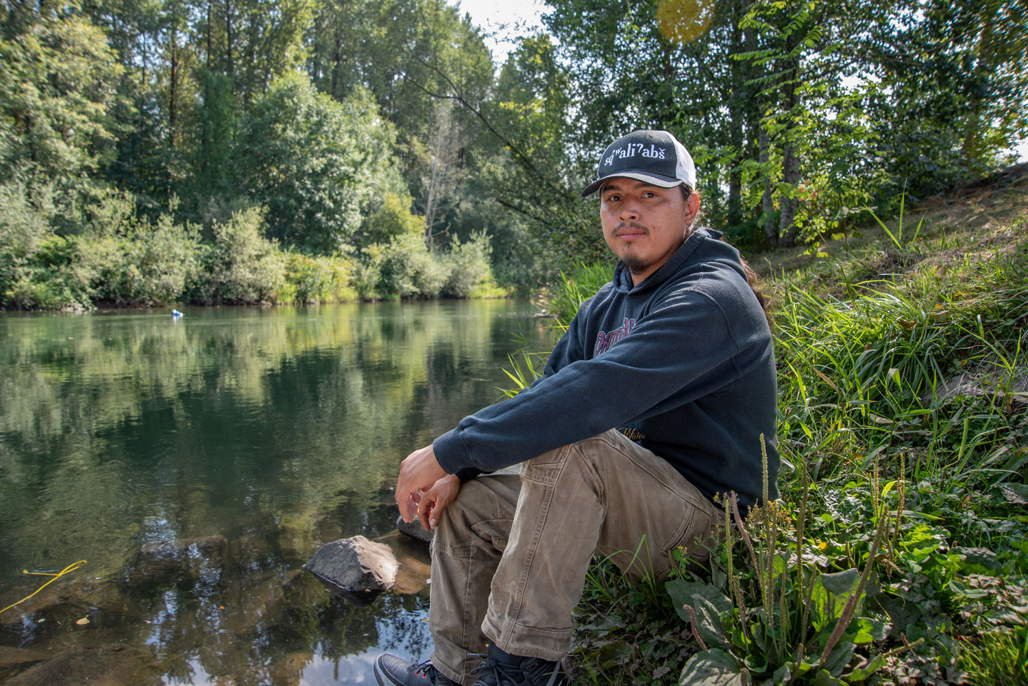 a young man poses beside a river