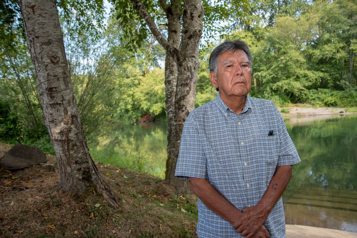 a man poses for a portrait by a river