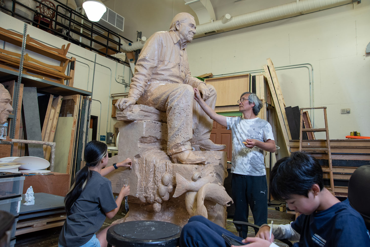 a man and children in a studio with a statue