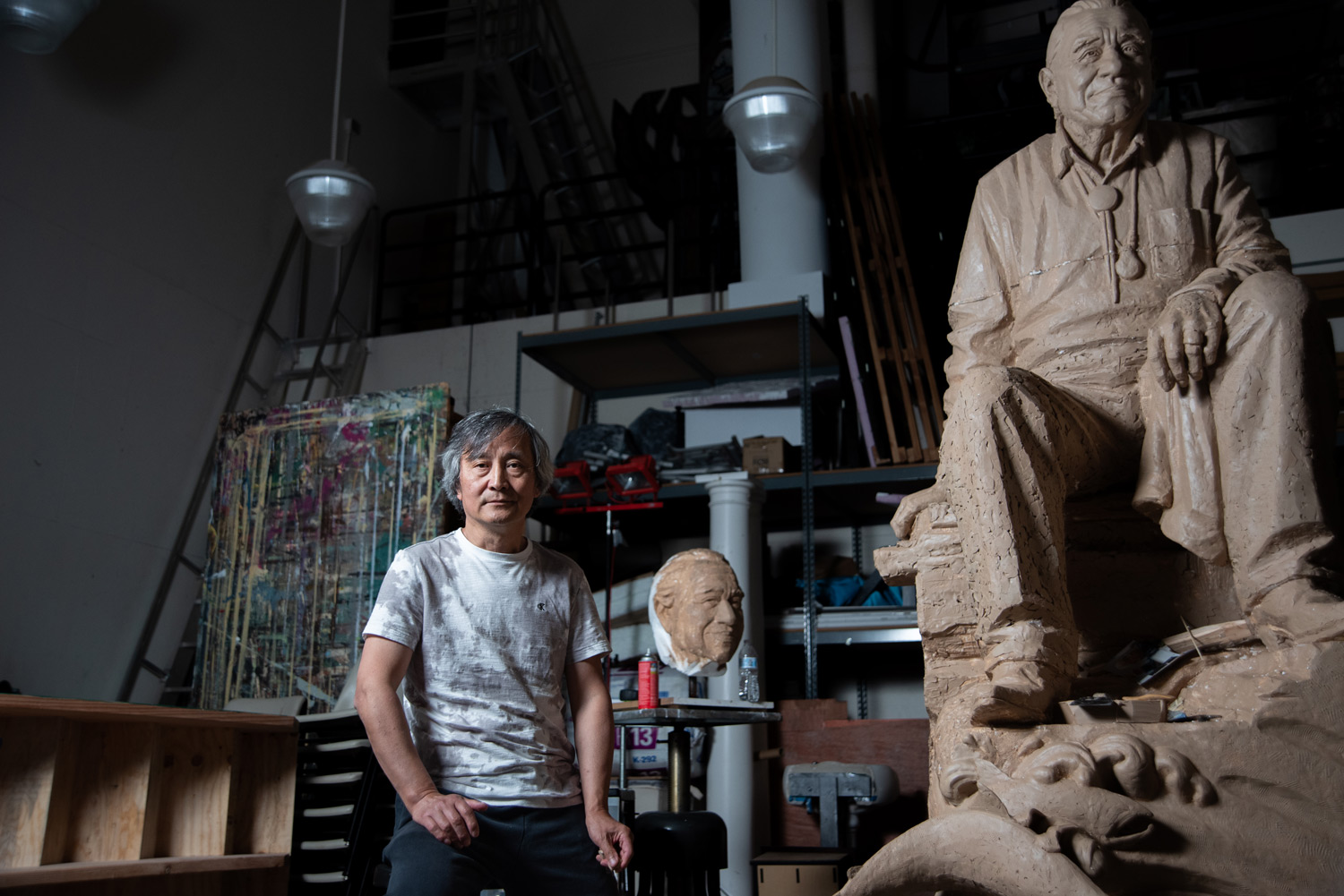 a man poses next to a statue