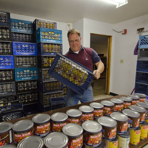 Joe Tice, the Tukwila Pantry's executive director, stocks tables with canned goods at the food bank in Tukwila, Washington. (Credit: Lance Cheung / USDA)