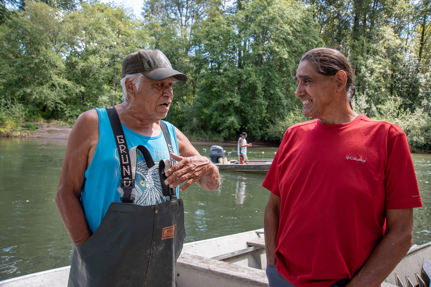 two men talk on the banks of a river