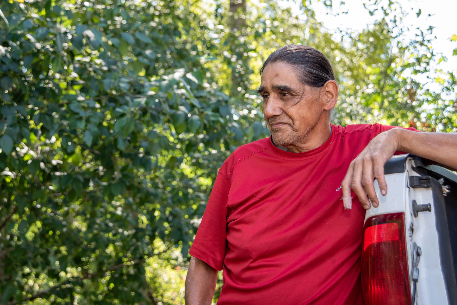 portrait of a man leaning on a truck in a red shirt