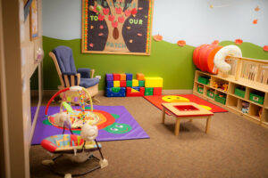 A daycare with colorful chairs, bouncers and blocks.