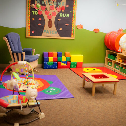 A daycare with colorful chairs, bouncers and blocks.