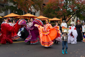 Dancers in colorful dresses walk in a parade