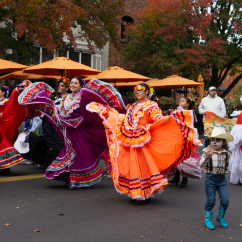 Dancers in colorful dresses walk in a parade