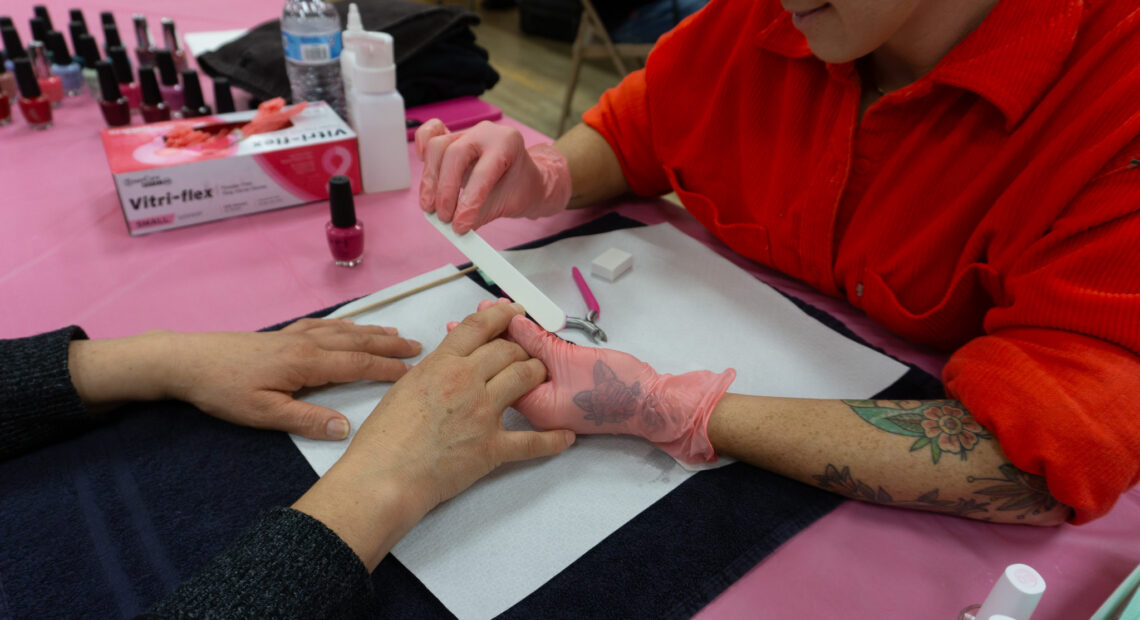 A woman in a red shirt gives a manicure.