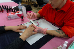 A woman in a red shirt gives a manicure.