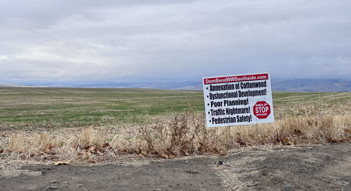 A white, red, and black sign against a green field.