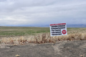 A white, red, and black sign against a green field.