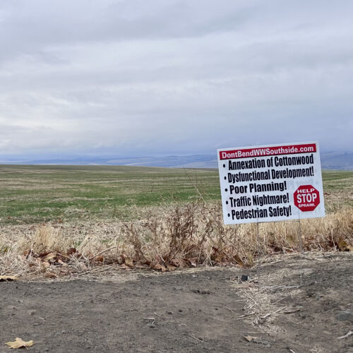 A white, red, and black sign against a green field.