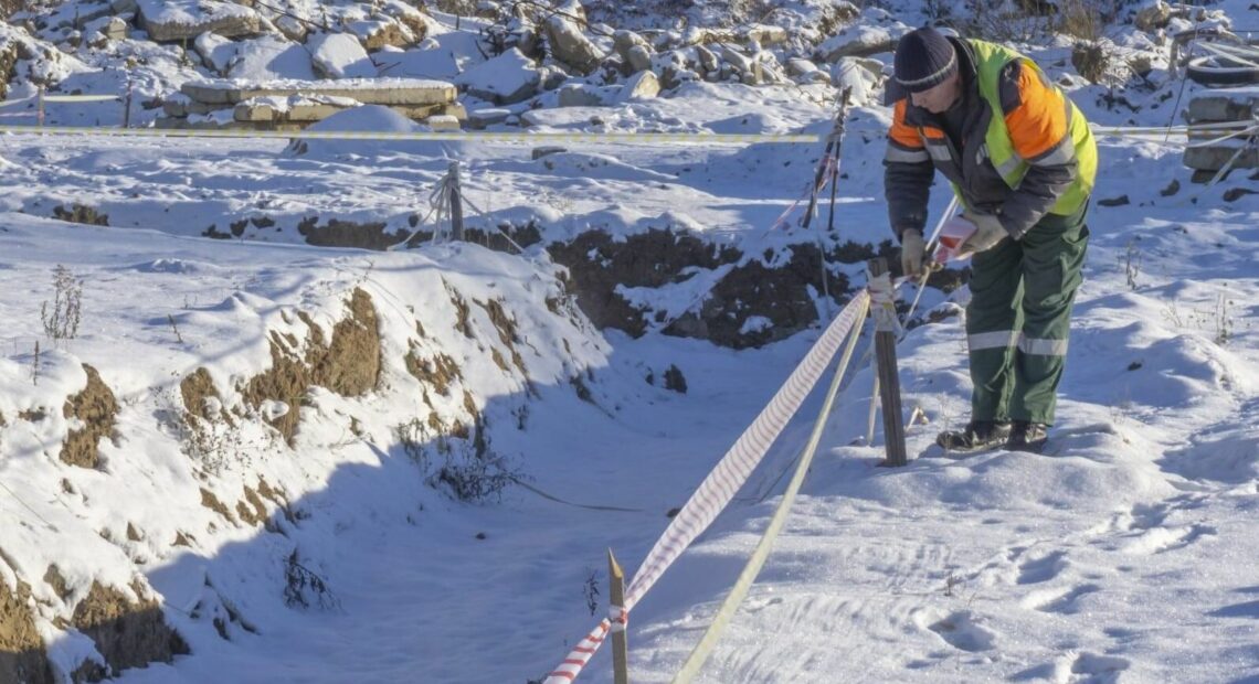 A person in a high-visibility vest works in the snow.