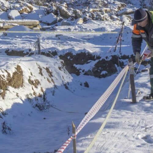 A person in a high-visibility vest works in the snow.