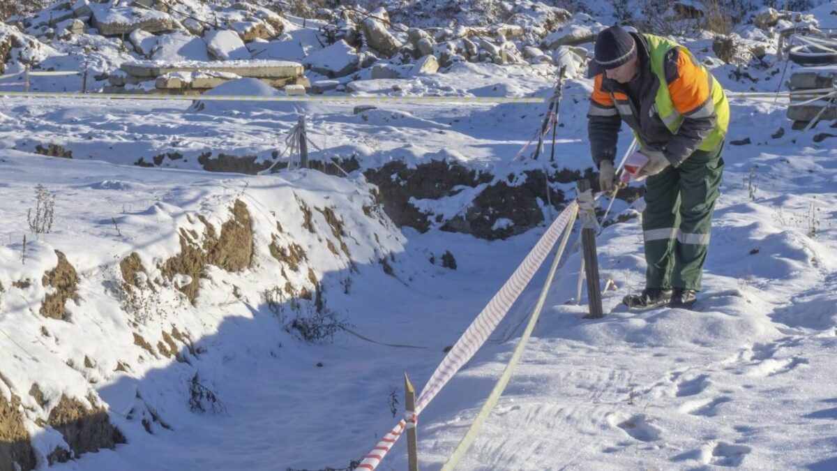 A person in a high-visibility vest works in the snow.