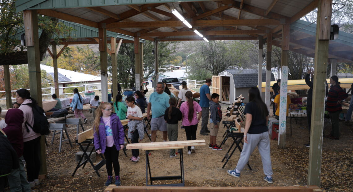 A group of children work on carving canoe paddle