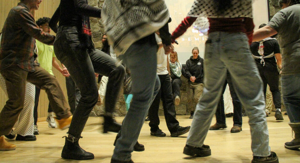 People's legs and feet are pictured as they dance in a circle.