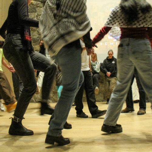 People's legs and feet are pictured as they dance in a circle.