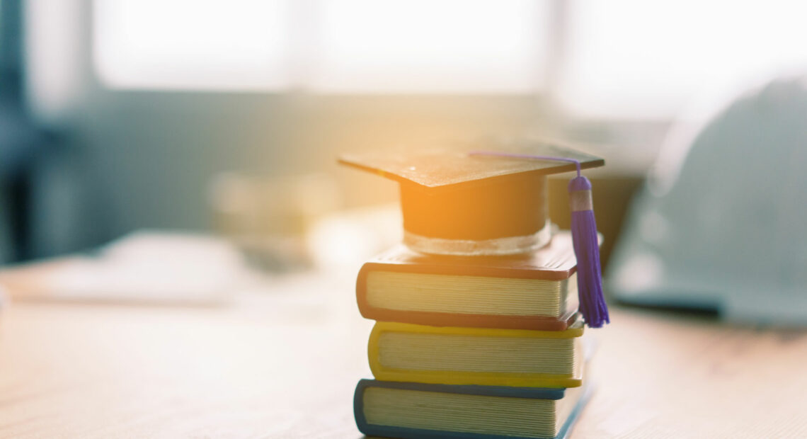 Libros y un birrete reposan sobre un escritorio. (Crédito: Adobe Stock Photos)