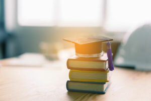 Libros y un birrete reposan sobre un escritorio. (Crédito: Adobe Stock Photos)