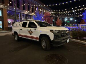 A white truck in front of Christmas lights.