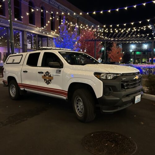 A white truck in front of Christmas lights.