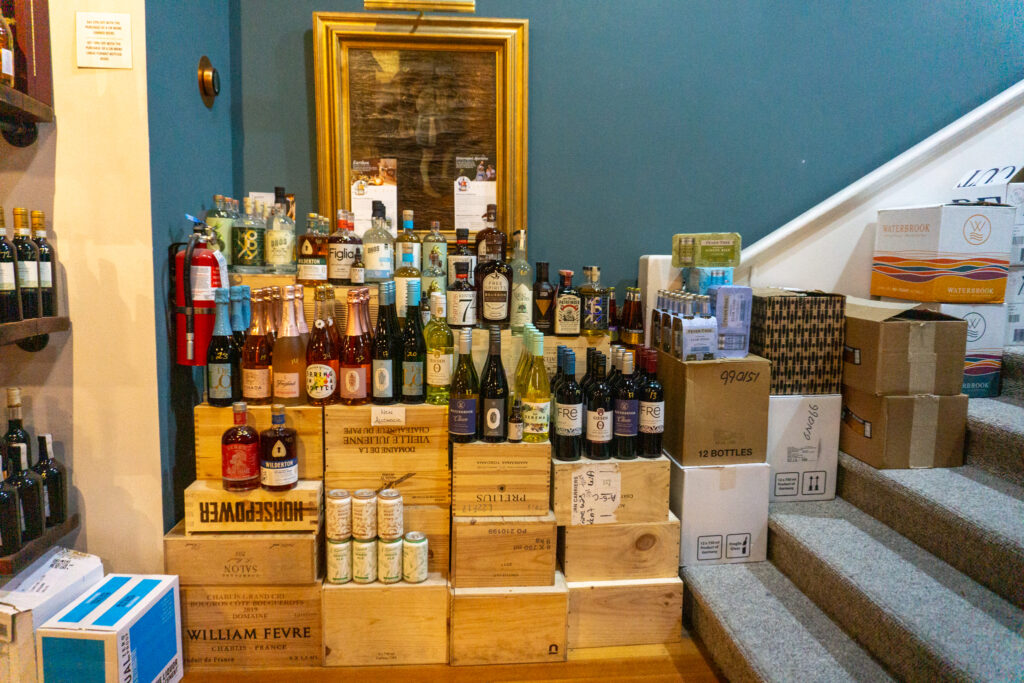 Dozens of colorful bottles sit on top of wooden crates. 