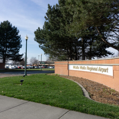 A brick wall leads into a parking lot. The sign reads "Walla Walla Regional Airport"