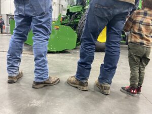 Farmers, and a future farmer, regard a new John Deere swather at RDO, a large tractor dealership in Pasco.