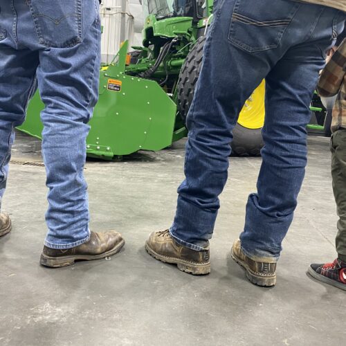 Farmers, and a future farmer, regard a new John Deere swather at RDO, a large tractor dealership in Pasco.