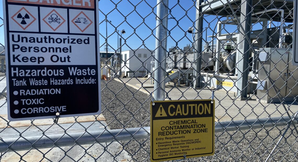 A gate and signs stand guard at one of the Hanford site’s tank farms.