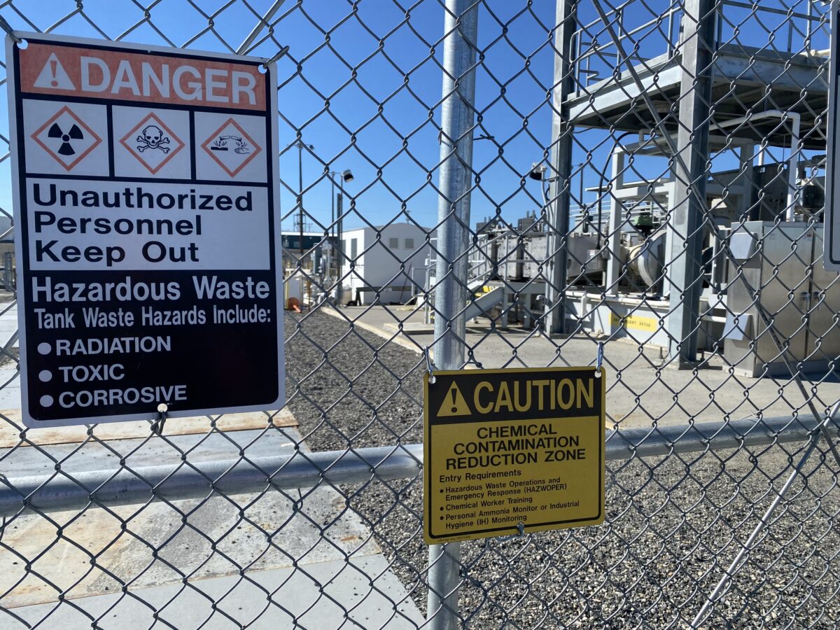 A gate and signs stand guard at one of the Hanford site’s tank farms.