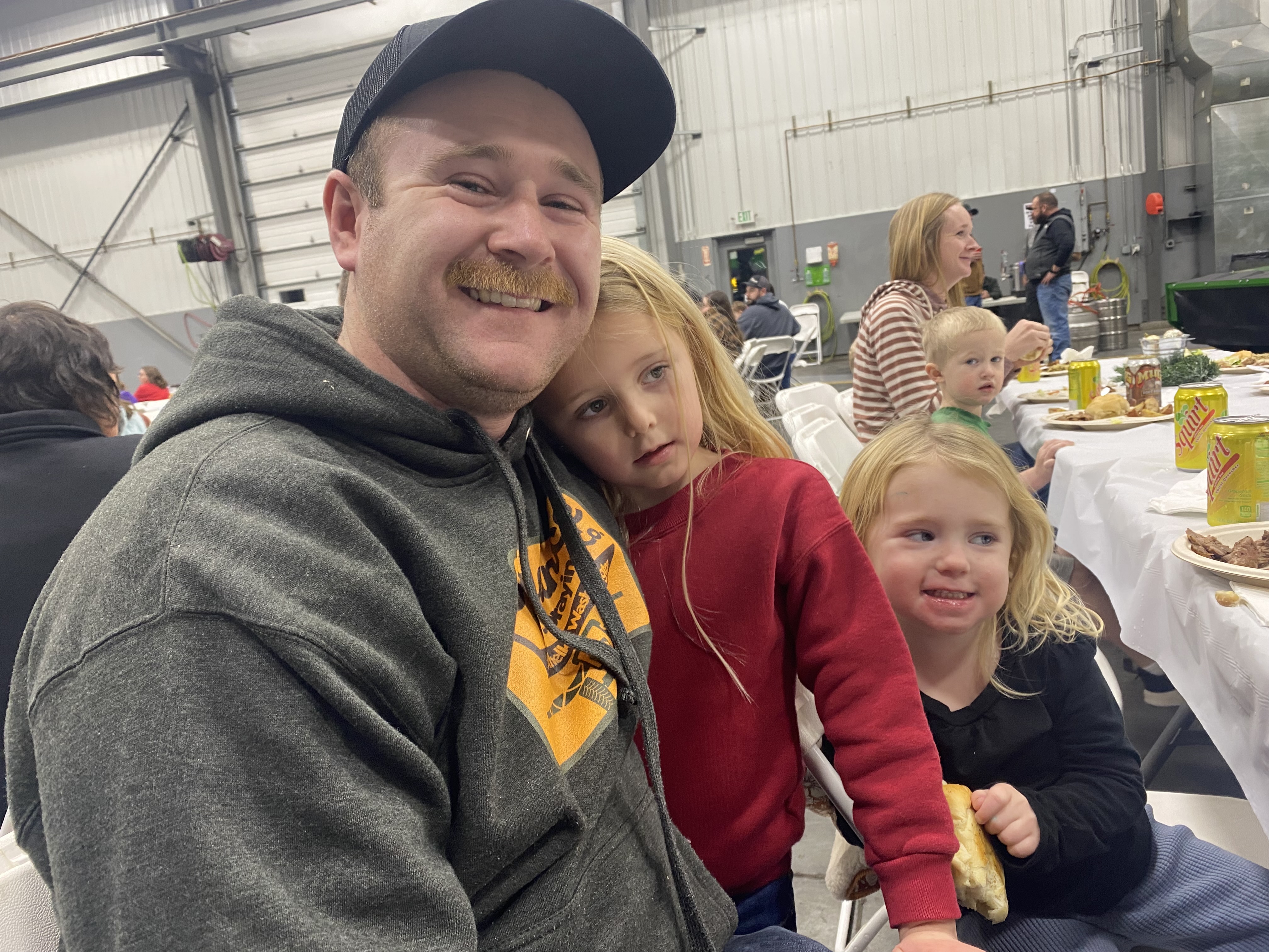 Austin Roylance, of Othello, and his young daughter sit at a long banquet table flanked by massive agricultural tractors for a customer appreciation dinner at RDO in Pasco. He says he thinks the Trump administration will be good for agriculture. 