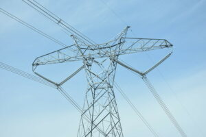 A gray transmission line is in front of a blue sky.