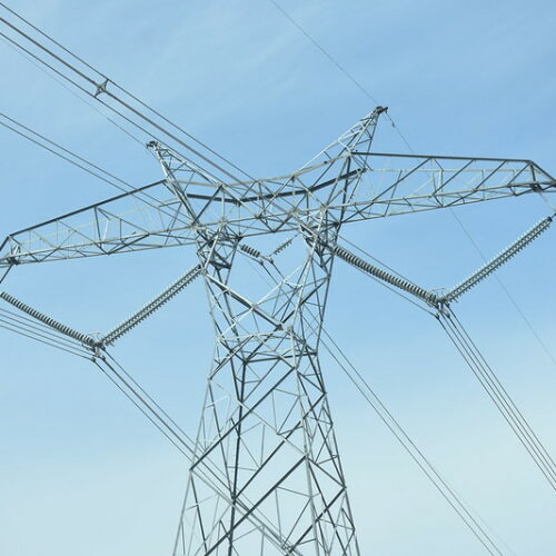 A gray transmission line is in front of a blue sky.