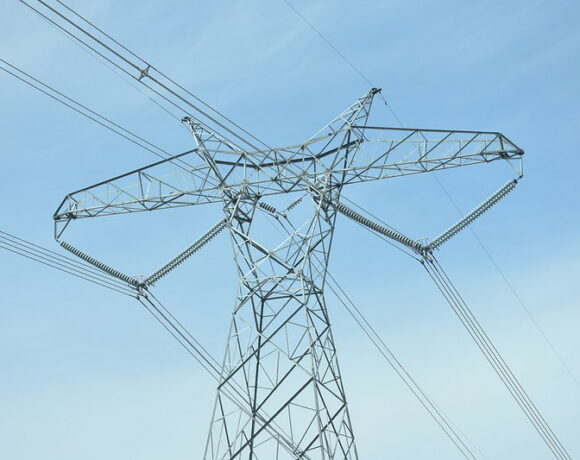 A gray transmission line is in front of a blue sky.