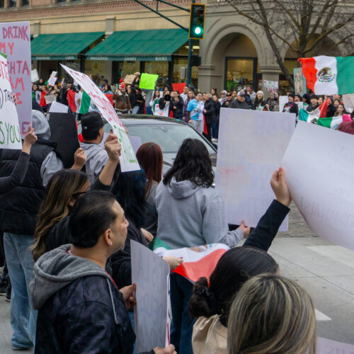 Group of people holding handmade signs and Mexican flags.